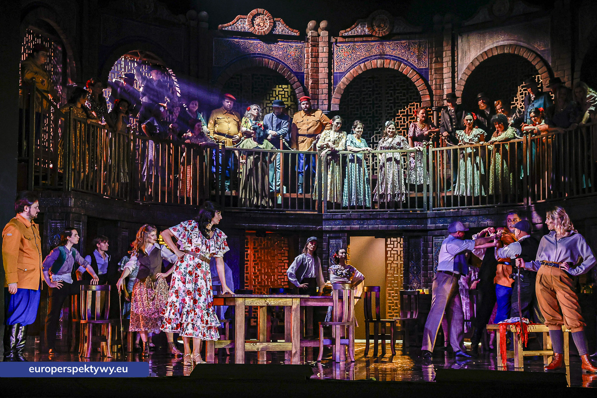 Scena zbiorowa z balkonem Chór na balkonie i scenie w fioletowym świetle, opera Carmen Georges'a Bizeta, Opera Śląska