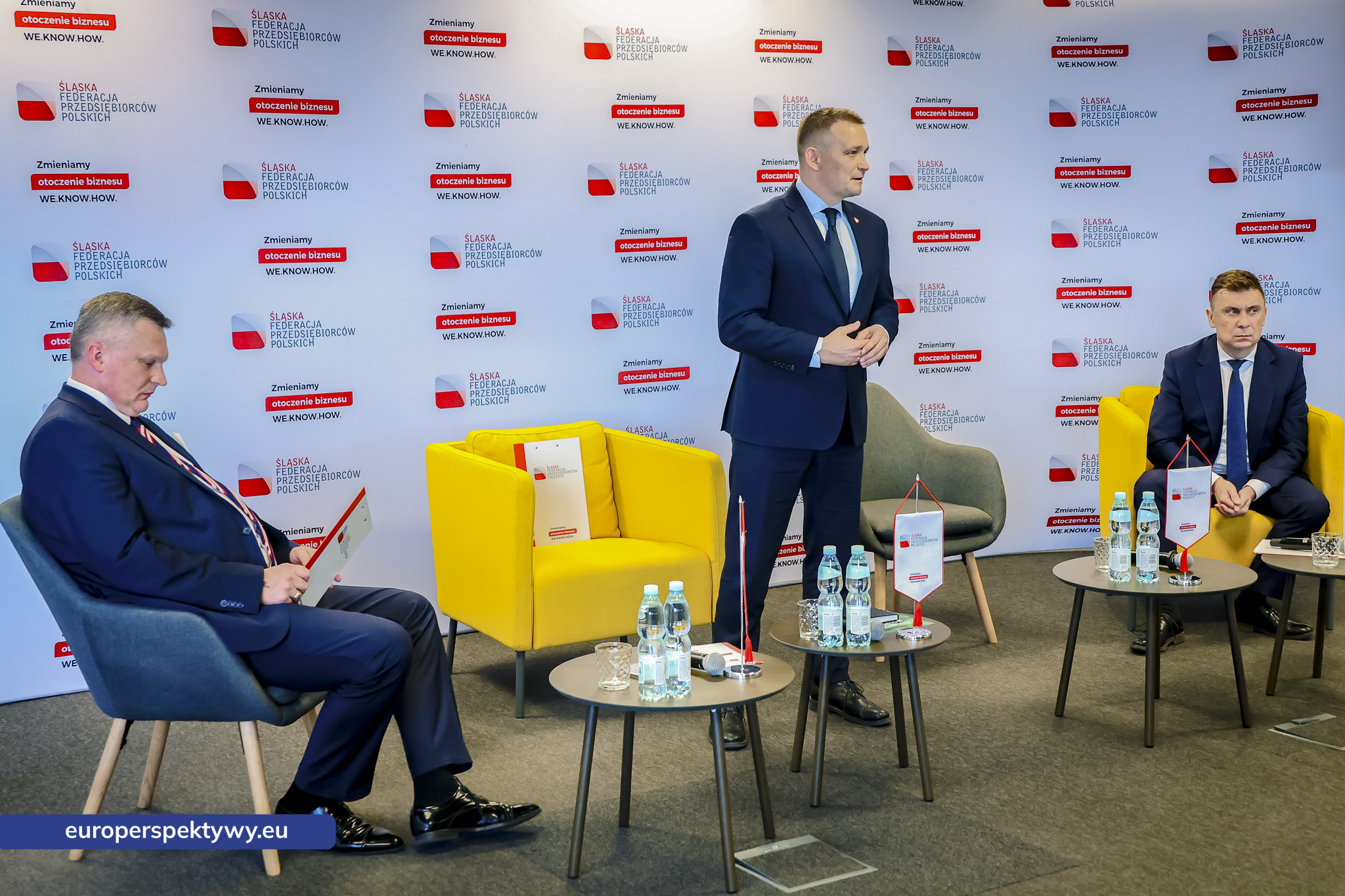 Wiceminister rozwoju i technologii Michał Jaros zabiera głos na stojąco, obok siedzą paneliści debaty ŚFPP